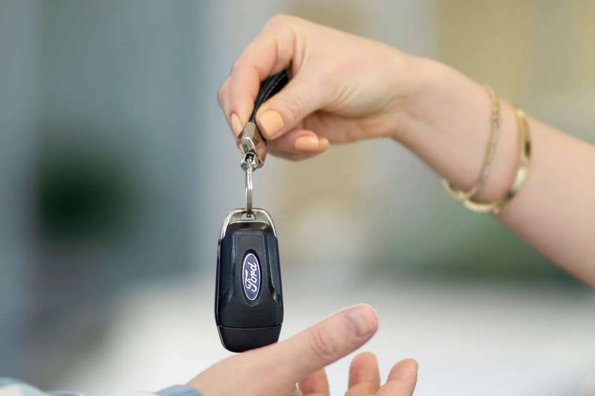 Chave do carro passando da mão do vendedor para a do comprador