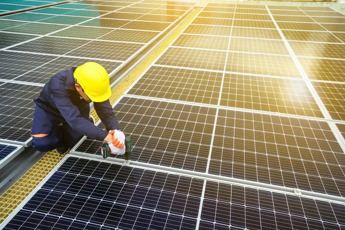 Instalador de capacete fixando uma placa solar com a parafusadeira
