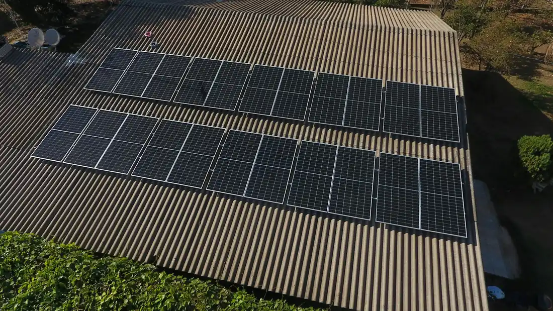 Duas fileiras de placas solares num telhado de telha ondulada, vistas de cima